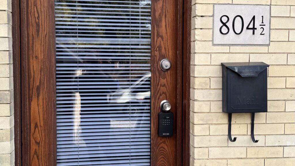 Front door with a deadbolt, a realtor lockbox on the handle and a mailbox beside it