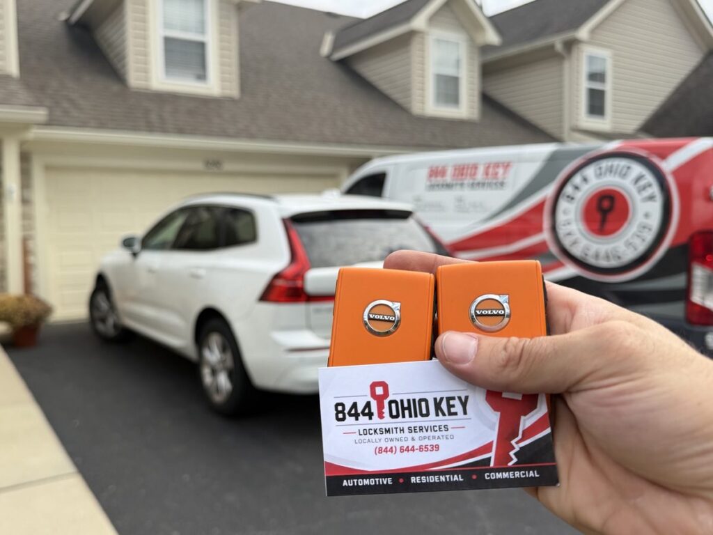 Locksmith Dublin Ohio job: two new OEM Volvo orange key fobs with an 844 Ohio Key business card, the customer’s Volvo and our van behind