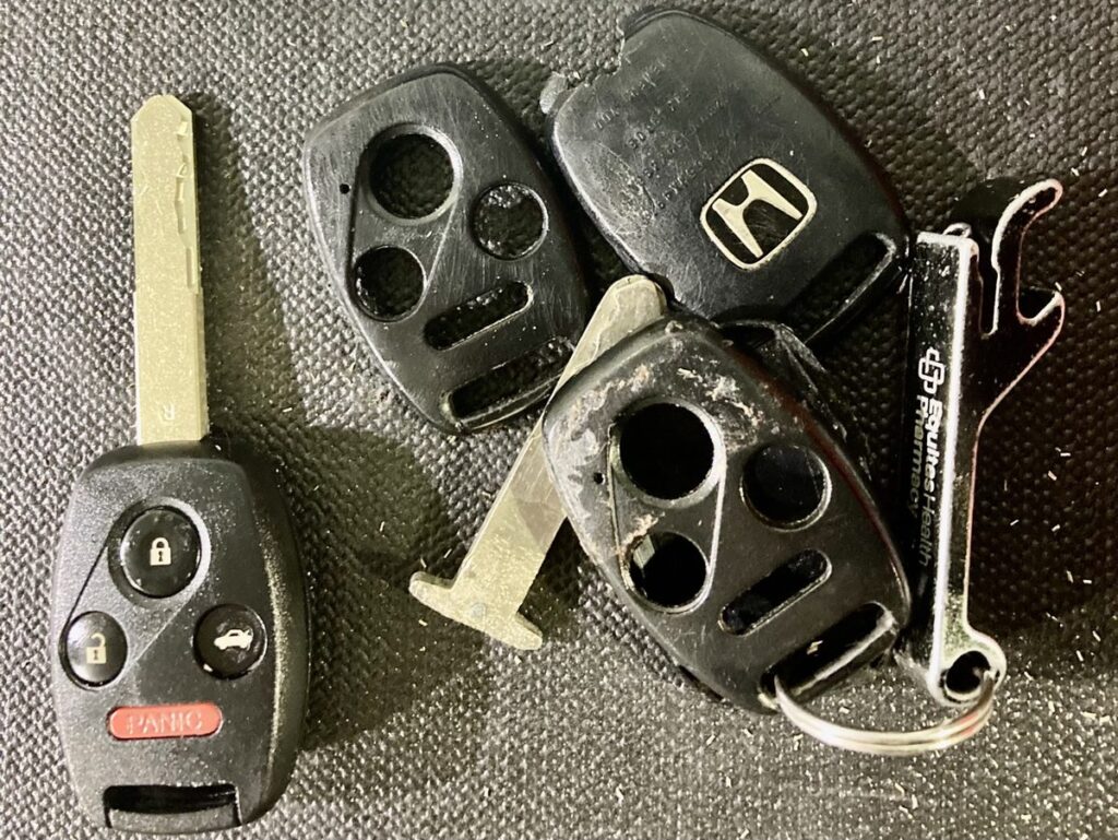 Broken Honda remote key next to the new key fob replacement, already cut