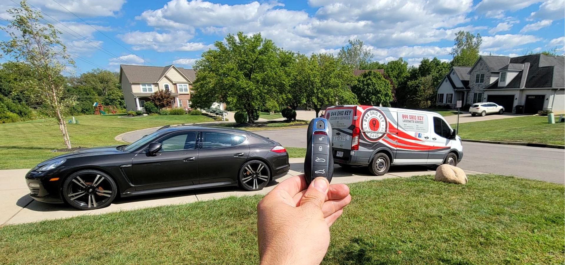 Locksmith holding a Porsche key with a Porsche and the 844 Ohio Key van behind it