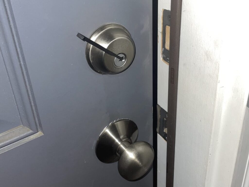 House lockout service: silver Schlage deadbolt just picked open, with the door slightly ajar